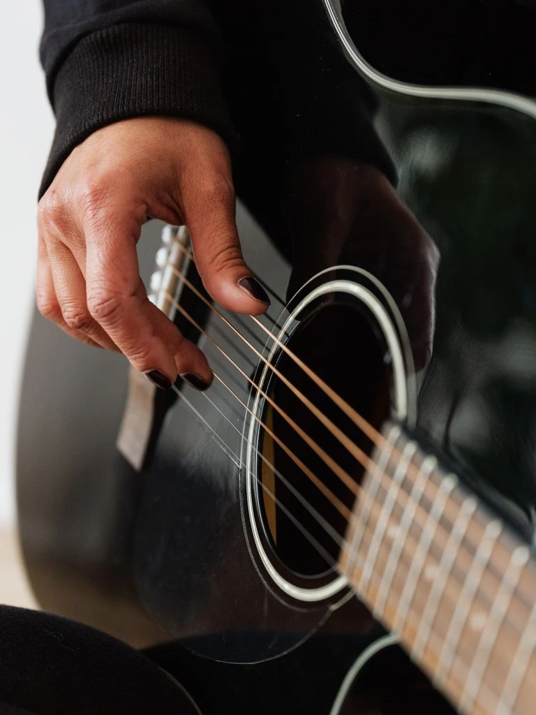 A musician's hands tuning a vintage hollow-body guitar.