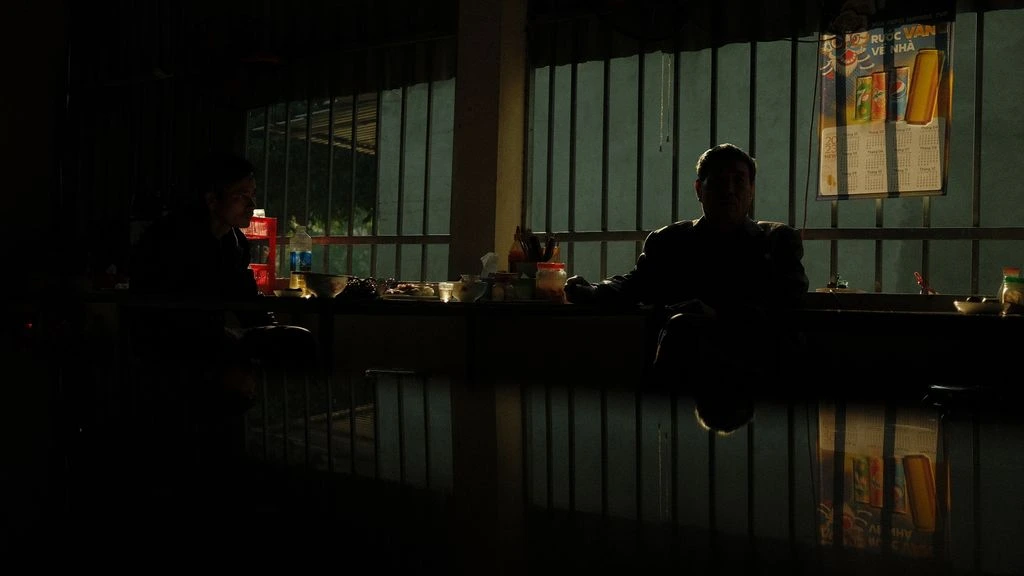 A solitary technician walks a darkened datacenter aisle at night, tablet in hand.